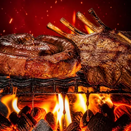 A boerewors coil and a rack of lamb dripping fat into the flames